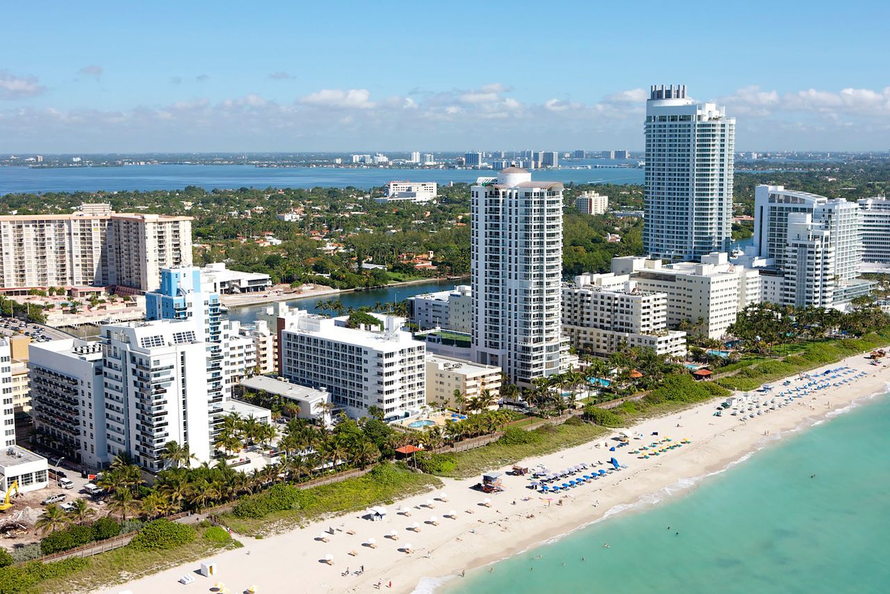 Stunning aerial view of Miami Beach's skyscrapers lining the pristine coastline under a clear blue sky.